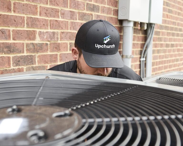 An Upchurch employee performing service on an HVAC unit