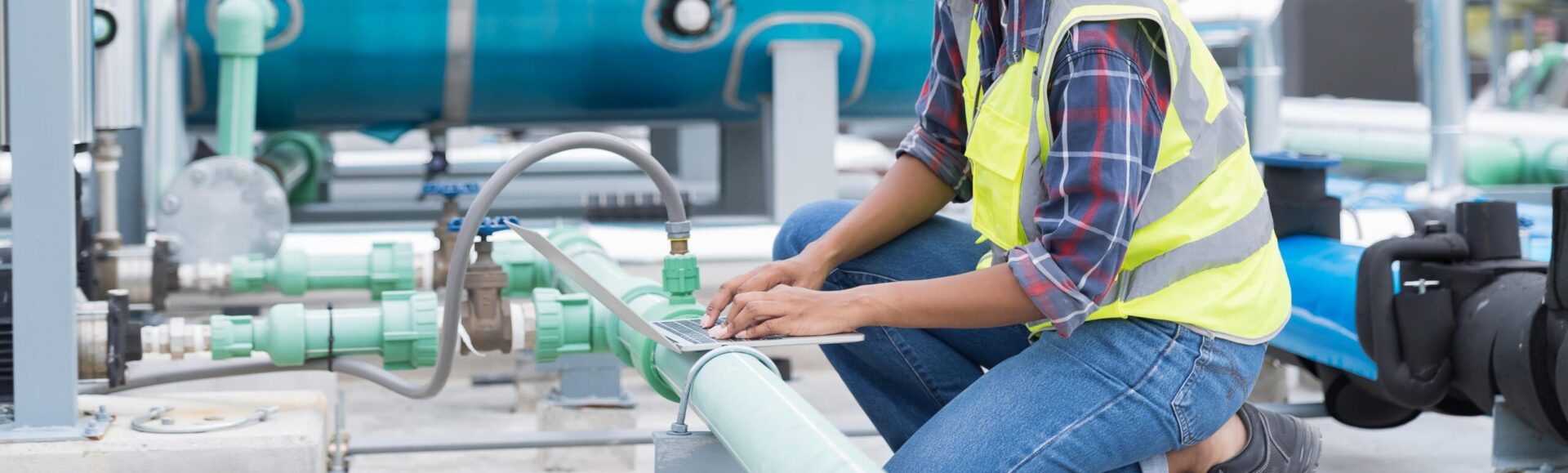 A technician examining an outdoor piping system