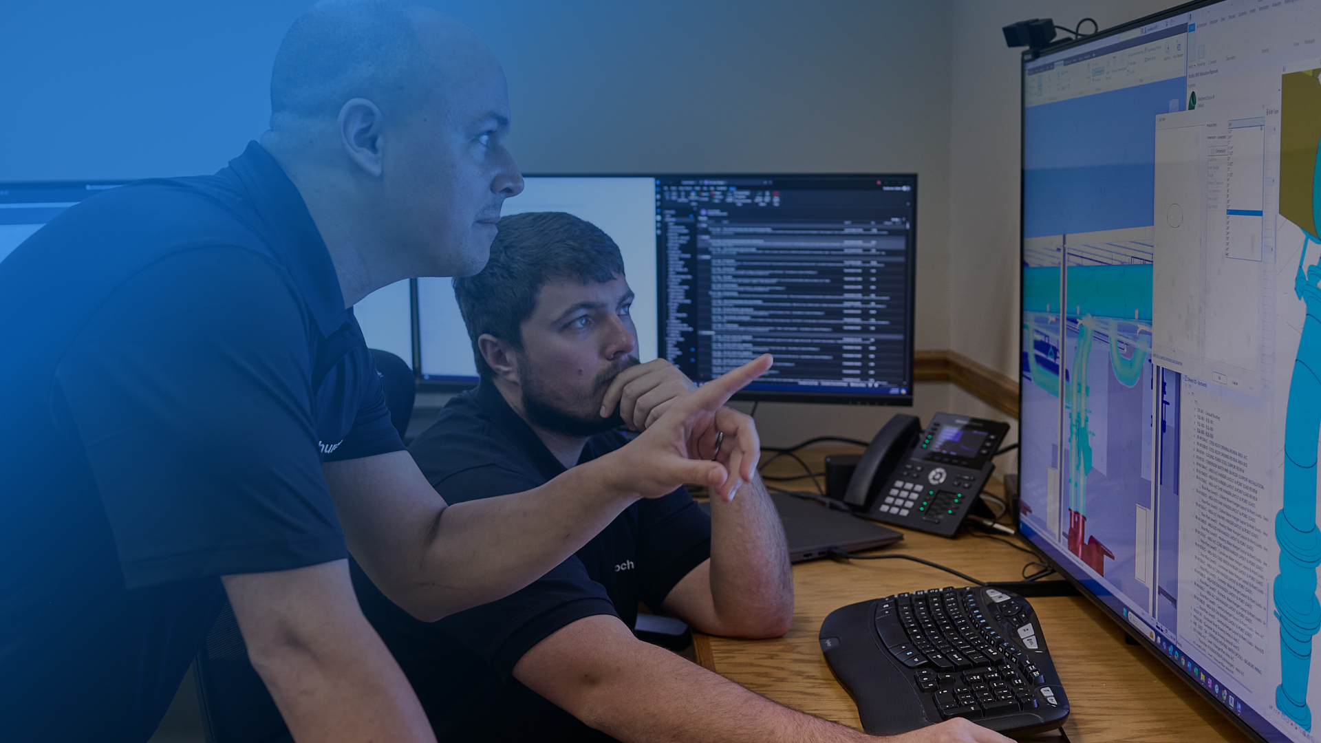 Two Upchurch employees closely reviewing plans on a large screen